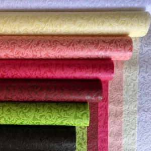 Več rol ovojnega papirja z vzorcem v različnih barvah, zloženi en na drugega