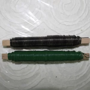 Dve leseni palici z navitimi žicami v barvah črna in zelena na svetli površini